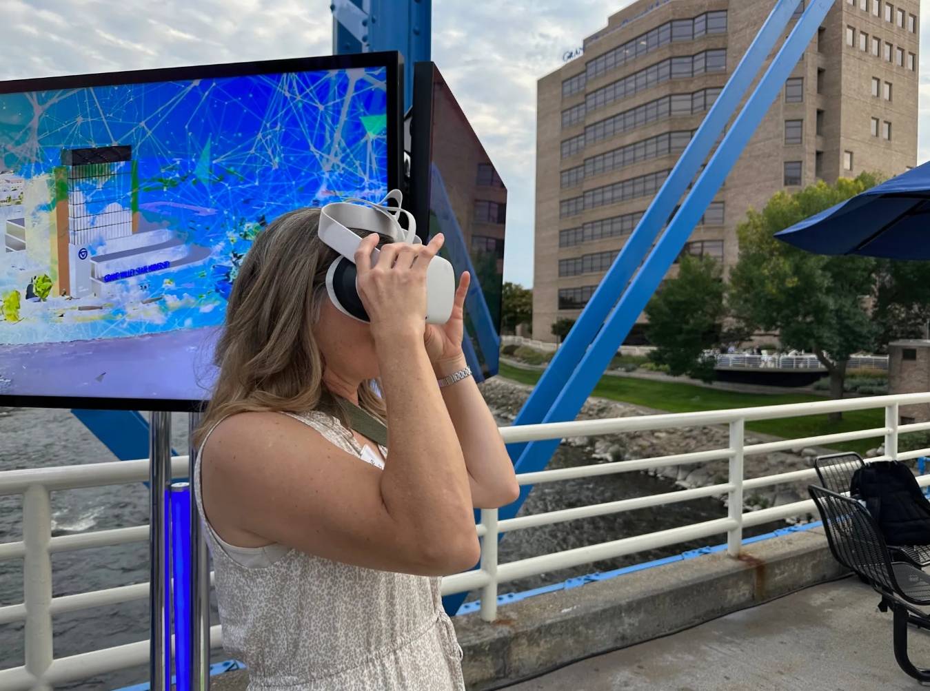 Woman with headset on Blue Bridge in Grand Rapids viewing virtual reality.